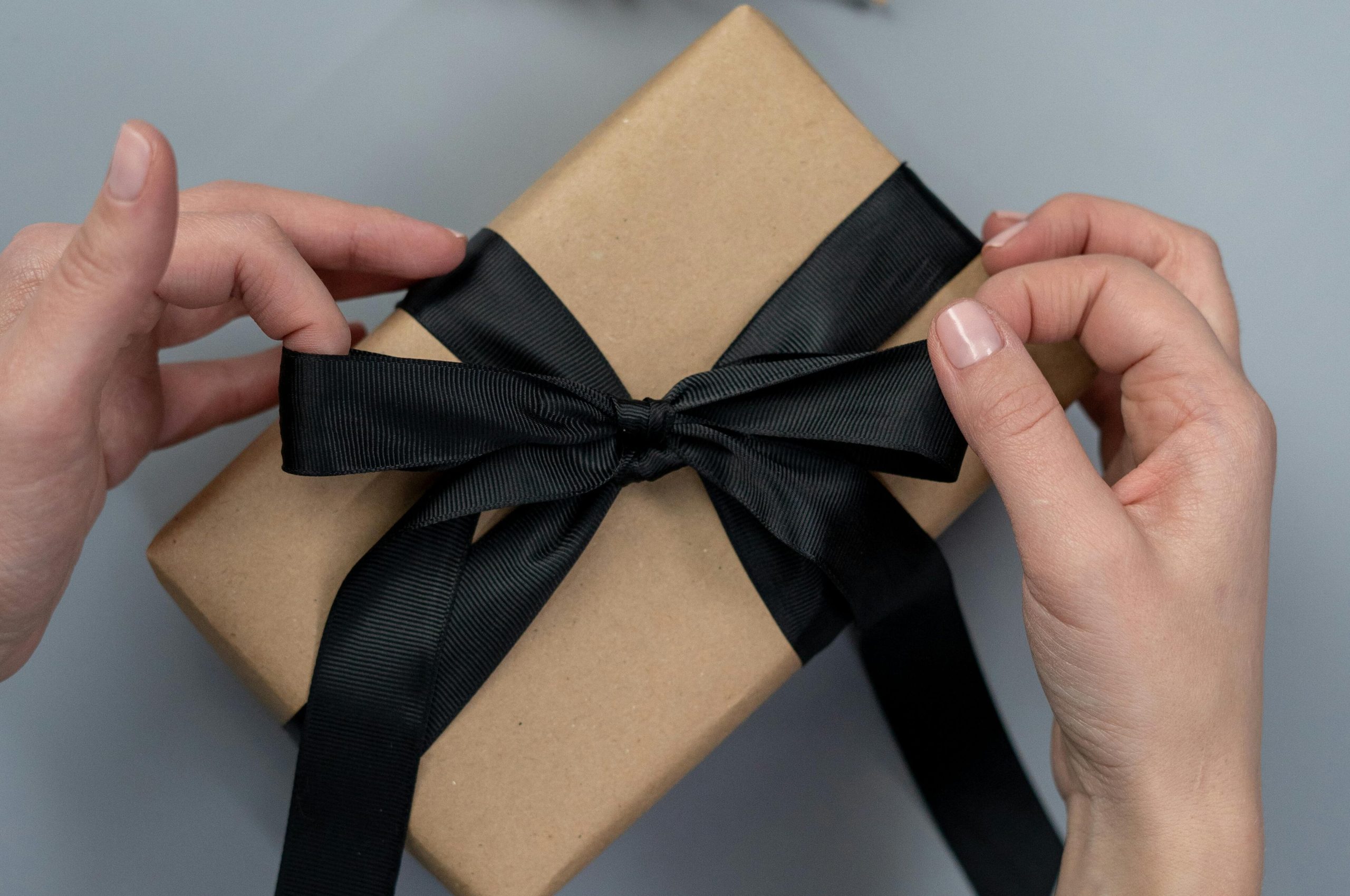 imatge Regalar una biografia personal, mans fent un llaç a un paquet